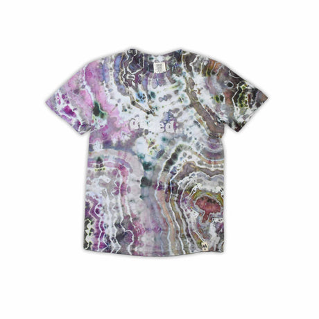 An artisanal ice-dyed t-shirt, its surface a canvas of swirling blues, purples, and chartreuse resembling geode formations, with the text 'dazed' in a stylized, icy lettering at the center.