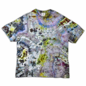 An artisanal ice-dyed t-shirt, its surface a canvas of swirling blues, purples, and chartreuse resembling geode formations, with the text 'dazed' in a stylized, icy lettering at the center.