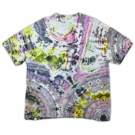 An artisanal ice-dyed t-shirt, its surface a canvas of swirling blues, purples, and chartreuse resembling geode formations, with the text 'dazed' in a stylized, icy lettering at the center.