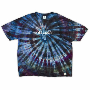 This t-shirt displays a stunning ice-dye technique creating a crystalline effect with vibrant blues, purples, and greens emanating outwards, with 'dazed' situated in the middle in a funky font.