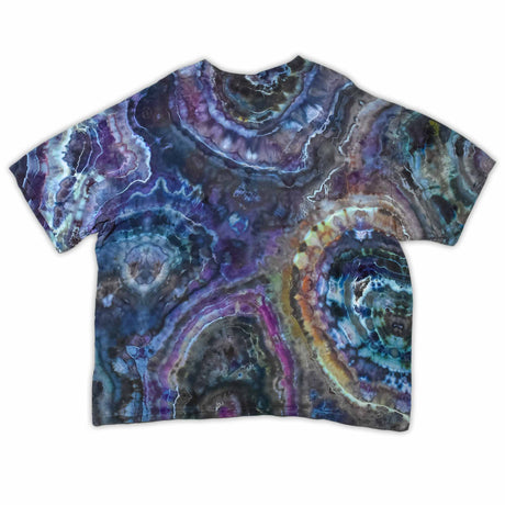 The vibrant patterns of this tie-dye t-shirt are reminiscent of a sliced geode, with bands of blue, purple, and green that encircle the 'dazed' text, which glistens like a quartz inscription.