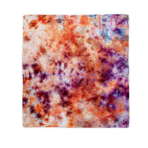 A hand-dyed bandana characterized by its ice-dyed effect, showcasing a storm of warm and cool colors, with prominent shades of rust and lilac resembling a nebula.