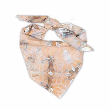 Earth-toned tie-dyed bandana displaying a symmetrical pattern with elements that suggest flowers and stars, in a soft palette of beige, grey, and white.