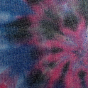 A pair of cozy sweatpants with a vibrant tie-dye pattern in shades of blue, pink, and dark navy, with a classic spiral design.
