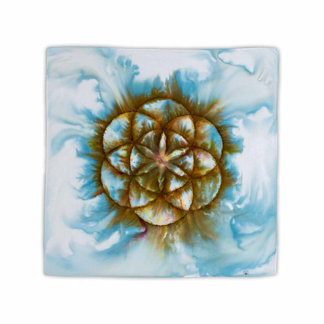 A hand-dyed bandana capturing the sacred geometry of the Seed of Life, ice-dyed in a blend of forest greens and browns, floating on a misty blue background.