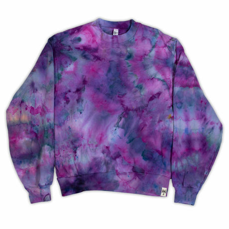 A tie-dye sweatshirt showcases a vibrant pattern of purples and blues, with colors merging fluidly. The ribbed cuffs and hem indicate a cozy and comfortable design.