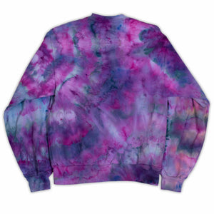 A tie-dye sweatshirt showcases a vibrant pattern of purples and blues, with colors merging fluidly. The ribbed cuffs and hem indicate a cozy and comfortable design.