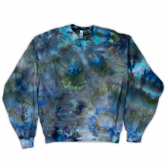 A cozy sweatshirt showcases an ice dye technique with a fusion of deep blues and soft greens, inviting a sense of calm and comfort."